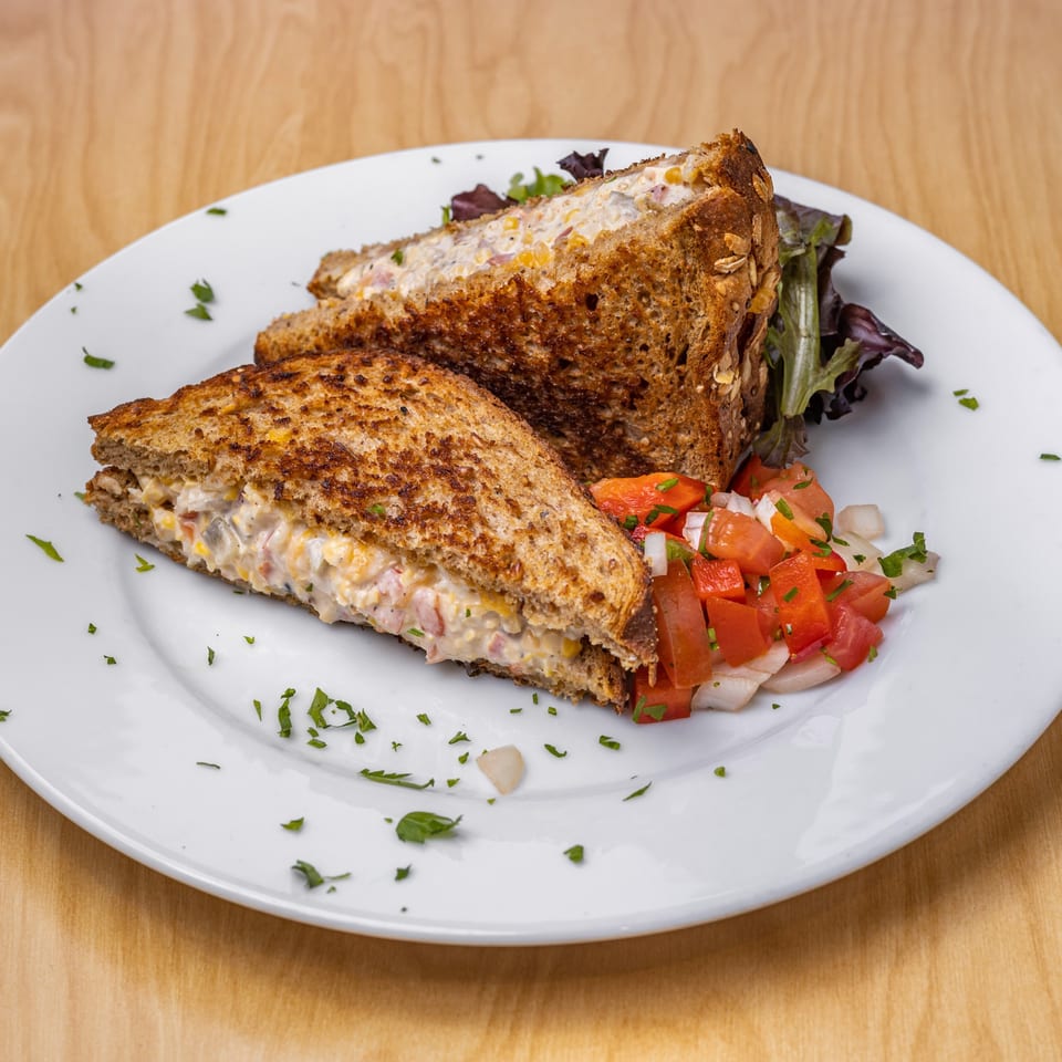 Vegan tuna melt sandwich with toasted bread, served with a side of fresh tomato and onion salsa.